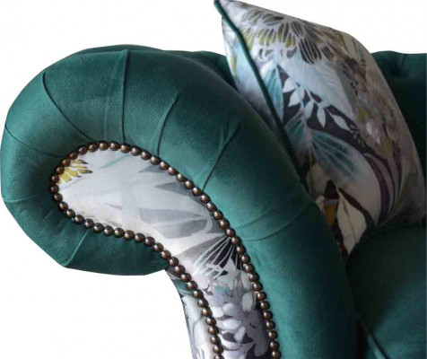A lively three-seater Chesterfield sofa in a delicate emerald color with a floral pattern.