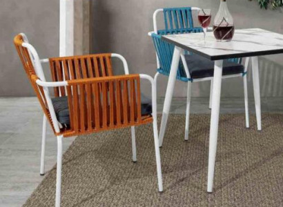 Original chair in light color on white legs with a soft seat cushion made of stainless steel.